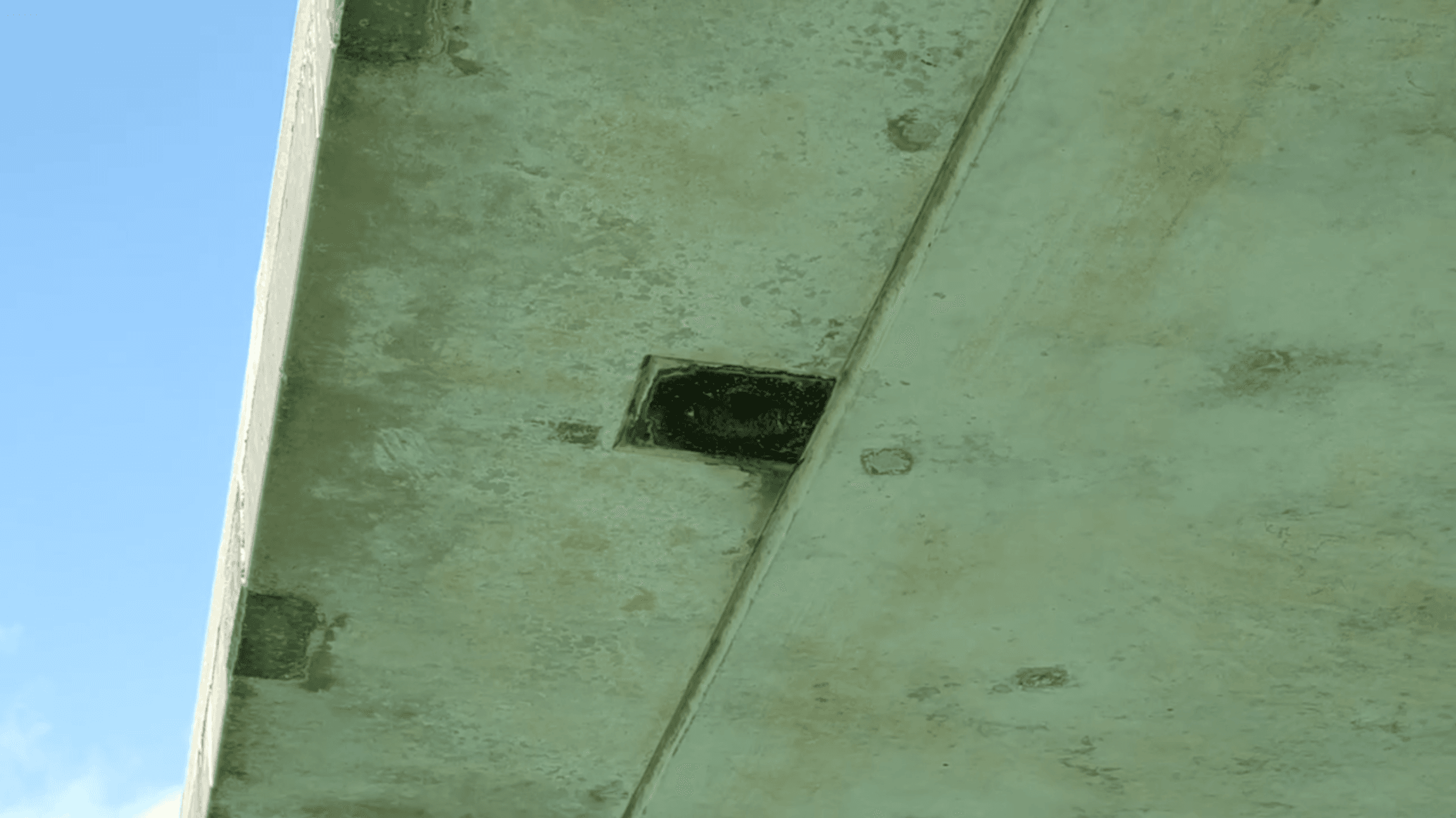 橋梁下方混凝土結構表面出現局部破損與剝落區域,中央可見一處明顯凹陷缺損,呈現橋梁結構巡檢中常見的劣化情況。